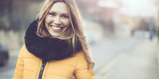 Smiling young woman in a yellow parka with a black fur collar